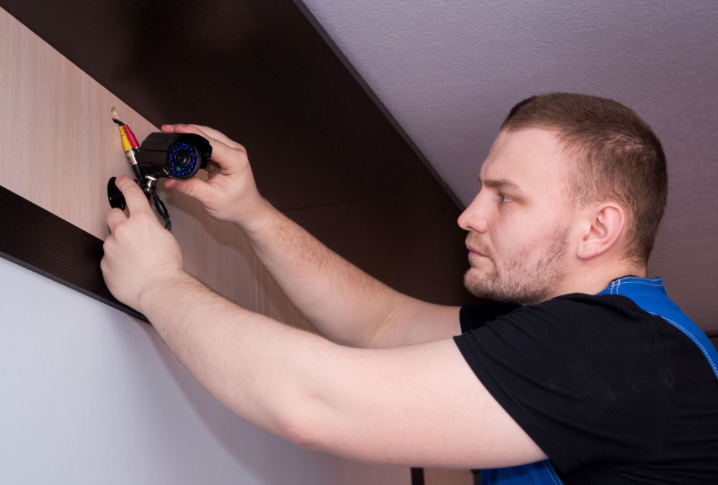 man mounting security camera to wall
